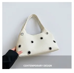 Detail of cream lychee leather underarm bag with decorative silver metal eyelets