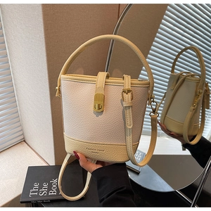 Détail d'un sac seau bicolore avec fermoir doré et texture en cuir de litchi