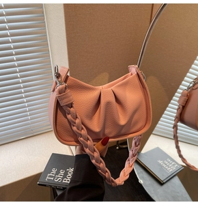 Detail of pink pleated underarm bag with thick woven strap and silver hardware texture