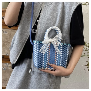 Detail of hand-woven crossbody bag with blue lattice patterns and lace bow accessory