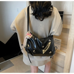 Detail of black leather crossbody bag with silver butterfly and plush bear charm
