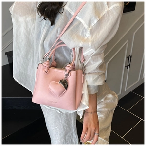 Detail of light pink lychee texture bucket bag with heart charm and silver buckle