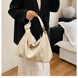 Close-up of beige pleated hobo bag with brown leather strap detail and knot accent