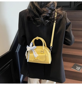 Detail of yellow pillow-shaped crossbody bag featuring a chic bow and checkered ribbon
