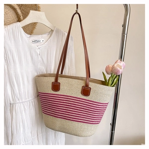 Dettaglio borsa tote in paglia intrecciata con strisce rosa e manici in pelle per l'estate