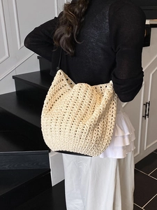 Beige woven crochet tote bag with black straps and bucket shape for women's daily use