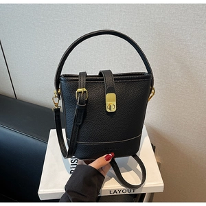 Détail du sac seau noir en cuir grainé avec fermoir doré et logo embossé