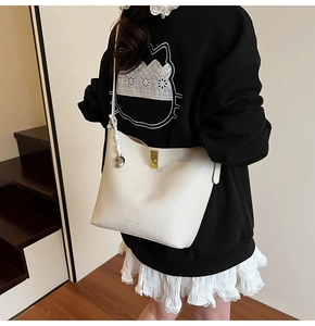 Detail of white lychee leather shoulder bag with gold buckle and silver heart pendant