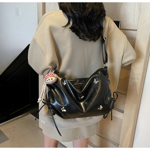 Detail of black pleated crossbody bag with silver butterfly charms on a model
