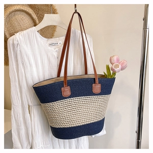 Dettaglio di una borsa tote in paglia intrecciata a righe blu e beige con manici marroni