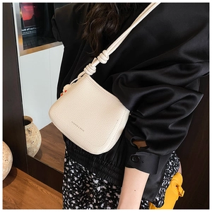 Detail of off-white lychee grain leather crossbody bag with knot strap and fashion text