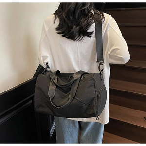 Close-up of black multifunctional travel bag with wide shoulder strap and side zipper pocket