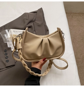 Detail of beige pleated cloud bag with woven handle on an artistic lifestyle background