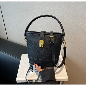 Détail d'un sac seau en cuir grainé noir avec fermoir doré tournant et texte Fashion Trend