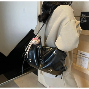 Detail of black pleated crossbody bag with butterfly metal ornament and plush charm