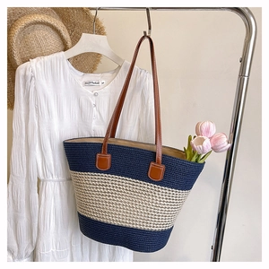 Dettaglio della borsa tote intrecciata a righe blu e beige con accessori estivi