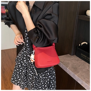 Close-up of red lychee textured bucket bag with a cute carrot rabbit charm detail