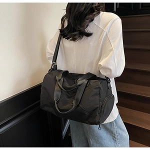 Side view of black nylon travel bag showing separate shoe compartment and shoulder strap