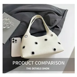 Detail of cream leather shoulder bag with large silver grommets and pebble grain texture