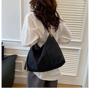 Detailed view of large black canvas hobo bag with brown leather trim and metal buckle