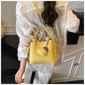 Detail of yellow bucket bag with litchi grain texture and heart pendant decoration