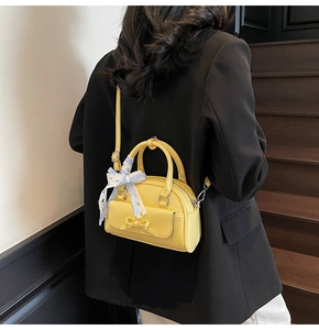 Detail of yellow semi-circular pillow bag with bow decor and blue checkered scarf wrap