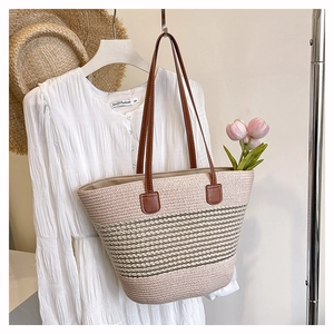 Dettaglio della borsa tote in paglia intrecciata con manici in pelle e righe