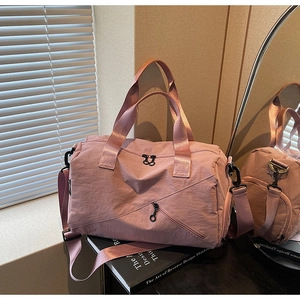 Detail of mauve nylon travel bag with adjustable strap and smooth metal hardware