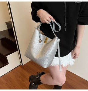 Close-up of silver lychee pattern leather bucket bag with gold buckle and heart charm