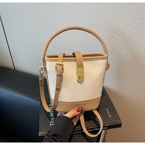 Détail du sac seau bicolore avec fermoir rotatif doré et bandoulière en cuir réglable