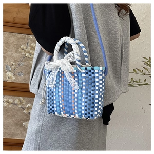 Close-up of woven crossbody bag featuring blue orange pattern and white lace bow detail