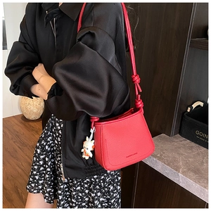 Red lychee texture bucket bag with knot strap and rabbit pendant detail shown on model