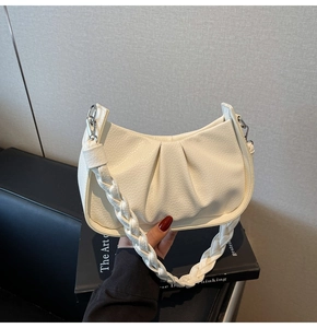 Detail of white dumpling bag with lychee texture and woven handle design