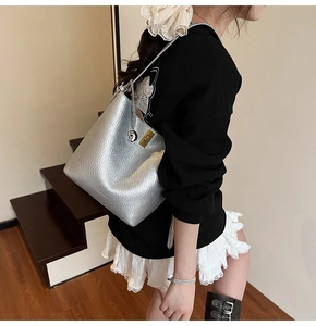 Silver metallic bucket bag with gold heart pendant shown on model in street style setting
