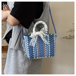 Detail of multi-color woven crossbody bag with lace bow and blue shoulder strap