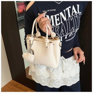 Detail of white bucket bag featuring litchi texture and unique knotted rope handle