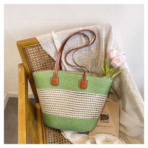 Dettaglio borsa tote in paglia intrecciata con strisce verdi e manici in pelle marrone