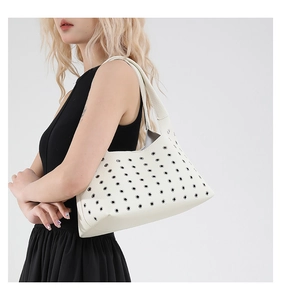 Detail view of white lychee leather underarm bag with silver metal eyelet rivet decor
