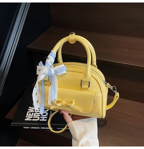 Detail of bright yellow leather shell bag with lace bow ribbon and silver hardware