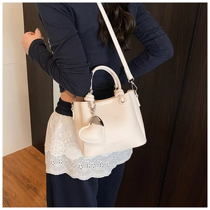 Chic beige bucket bag featuring lychee texture and heart charm in a street style look