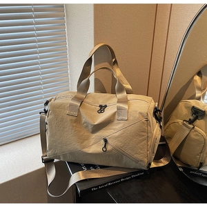 Close-up of beige nylon travel bag showing adjustable strap and diagonal zipper detail