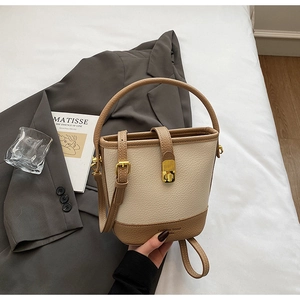 Détail du sac seau crème et beige en cuir grainé avec fermoir métallique doré élégant