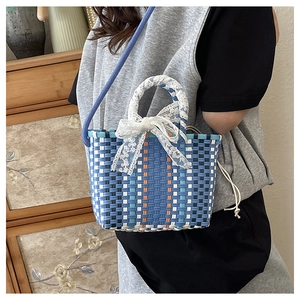 Detail of woven tote bag with lace bow decoration and blue rope shoulder strap