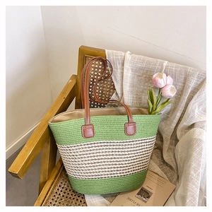 Dettaglio della borsa tote intrecciata verde e beige con manici in pelle marrone