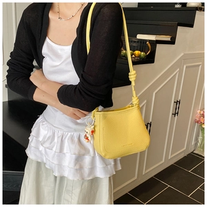 Detail of yellow bucket bag with lychee pattern leather and cute rabbit pendant