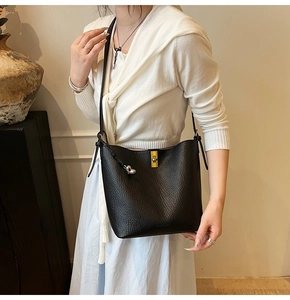 Detail of black pebbled leather bucket bag with gold clasp and silver heart charm decoration