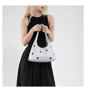 Detail of white textured leather shoulder bag with hollow metal grommets and chic rivet design
