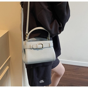 Détail de la texture du cuir grainé et de la boucle en métal doré haut de gamme sur le sac