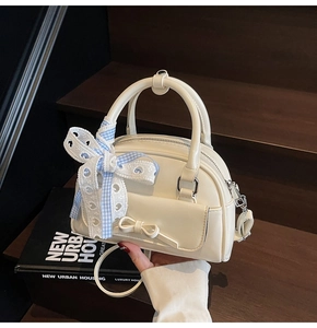 Detail of white Boston handbag featuring lace bow accent and adjustable shoulder strap