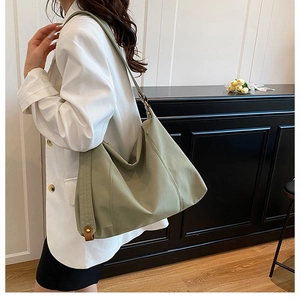 Detailed side view of green pleated tote bag with bronze metal buckle on model